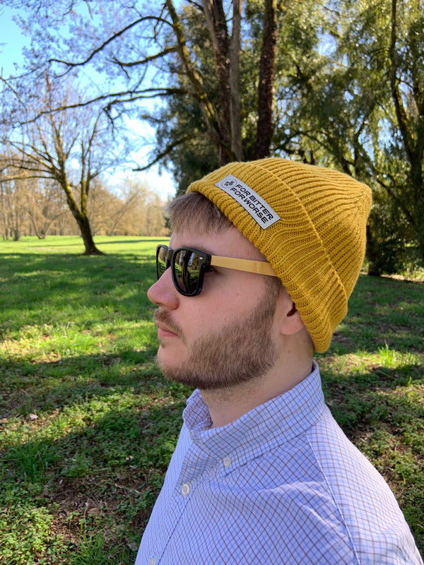 Close-up of a man wearing a knit beanie in golden yellow.