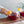 Load image into Gallery viewer, Close-up of two short glasses of a cherry-red non-alcoholic cocktail with orange peel garnishes.