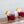 Load image into Gallery viewer, Close-up of two short glasses of a cherry-red non-alcoholic cocktail with orange peel garnishes.