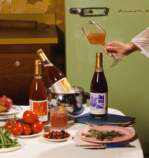 Table setting with three bottles of For Bitter For Worse, glasses, and food in a vintage kitchen.