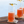 Load image into Gallery viewer, Close-up of four Collins glasses containing orange non-alcoholic cocktails with rosemary and lemon peel garnishes.
